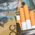 Open packet of cigarettes with $A50 note in the background.